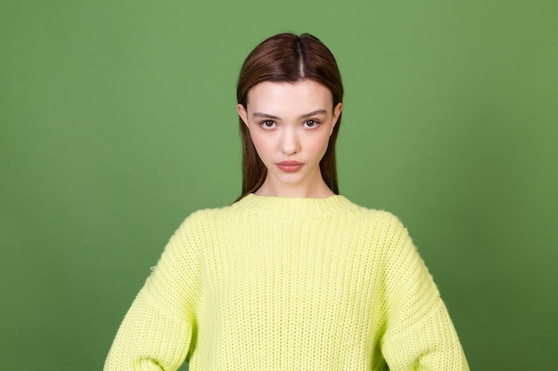 Gratis foto jonge vrouw met schone perfecte natuurlijke huid en make-up bruine grote lippen op groene muur poseren