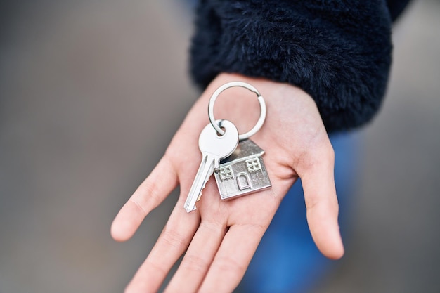 Gratis foto jonge vrouw met sleutel van nieuw huis op straat