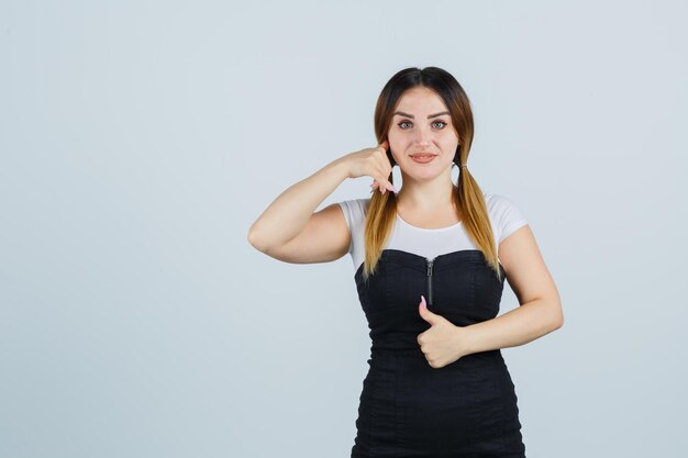 Jonge vrouw met telefoongebaar en duimen omhoog