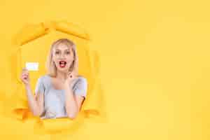 Gratis foto jonge vrouw met witte creditcard op geel oppervlak