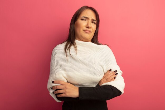 Jonge vrouw met witte sjaal die met armen gekruist op borst wordt ontevreden