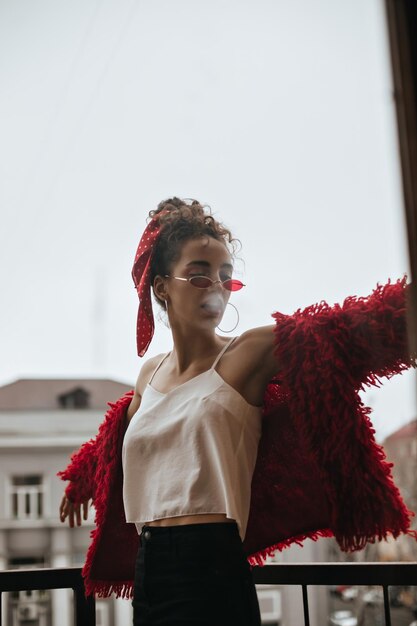 Jonge vrouw met witte top poseren op balkon