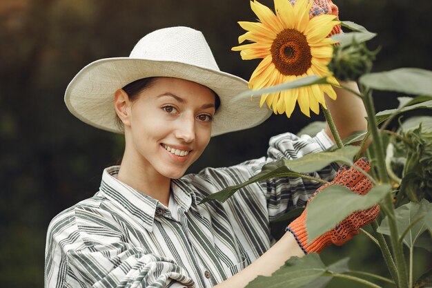 Jonge vrouw met zonnebloemen. Dame in een hoed. Meisje in een tuin.