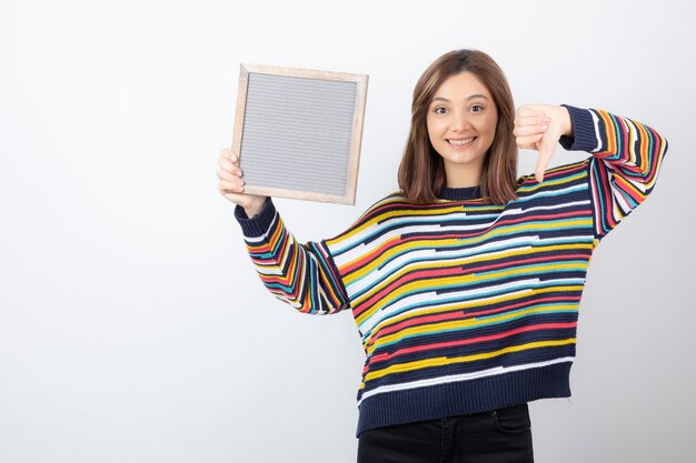 jonge vrouw model met een frame met een duim naar beneden.