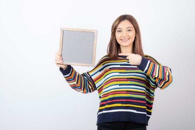 jonge vrouw model permanent en wijzend op een frame.