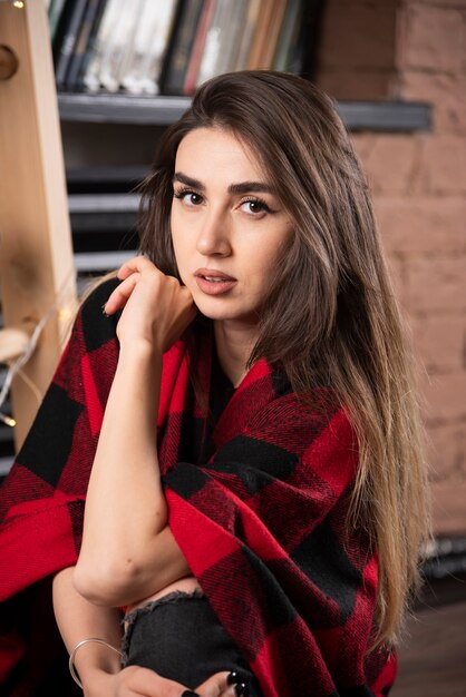 Jonge vrouw model poseren met geruite plaid in de buurt van kerstballen.