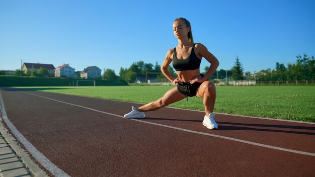 Jonge vrouw oefent side lunges in stadion