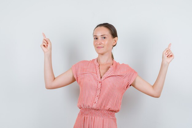 Jonge vrouw omhoog en waait wangen in gestreepte jurk vooraanzicht.