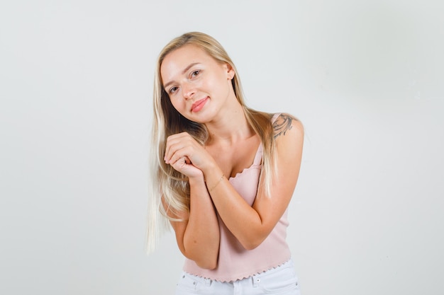 Jonge vrouw omklemde handen tijdens het poseren in singlet