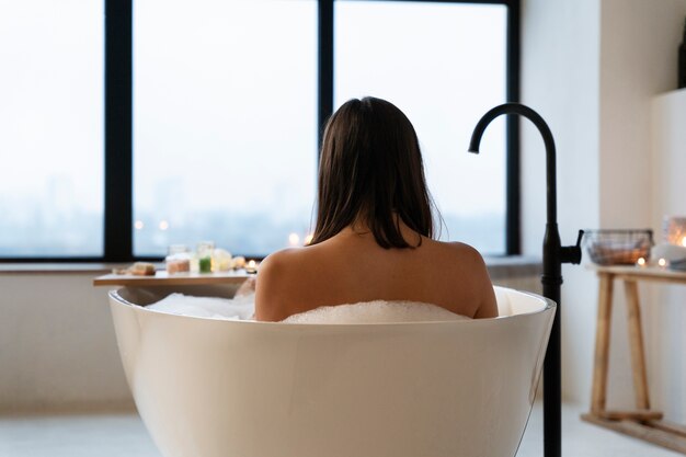 Jonge vrouw ontspannen in de badkuip die een bad neemt