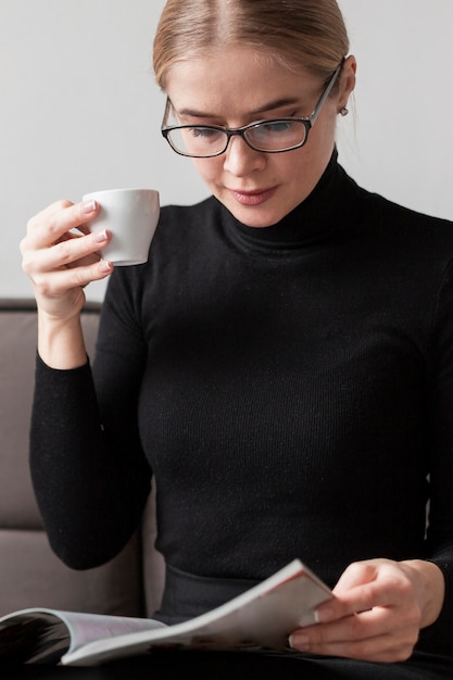 Jonge vrouw op bank koffie drinken