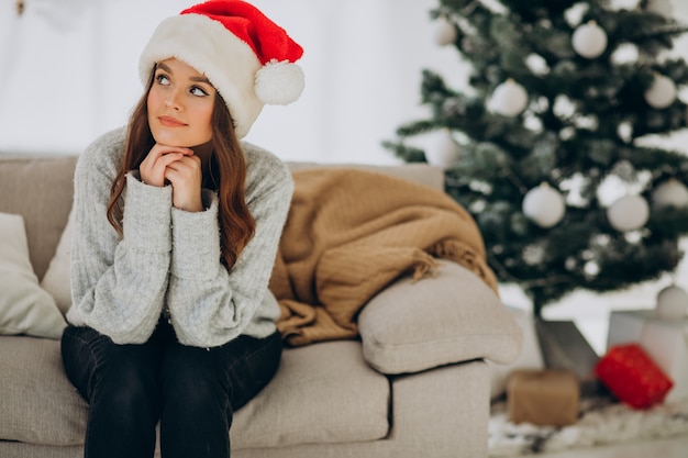 Jonge vrouw op de bank bij de kerstboom