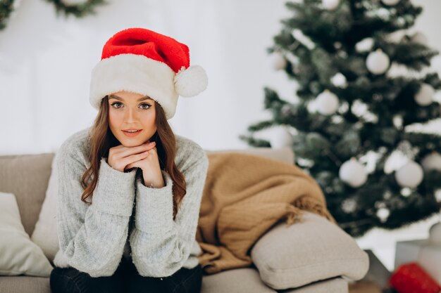 Jonge vrouw op de bank bij de kerstboom