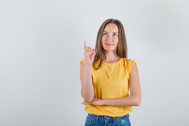 Jonge vrouw opzoeken met vinger teken in t-shirt