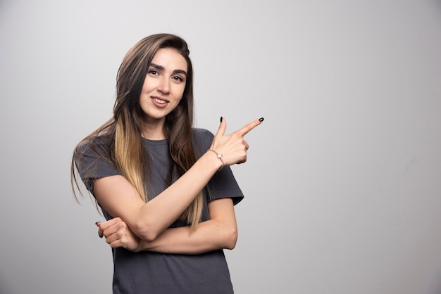 Jonge vrouw permanent en omhoog gericht op een grijze achtergrond.