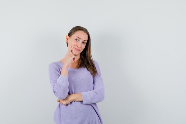 Jonge vrouw poseren in lila blouse en schattig kijken. vooraanzicht. ruimte voor tekst