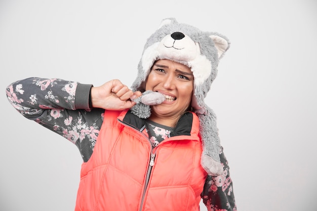 Jonge vrouw poseren met grappige hoed op een witte muur.