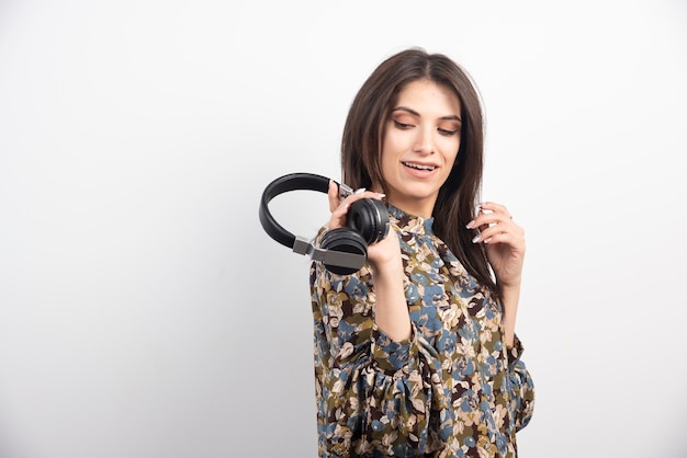 Jonge vrouw poseren met koptelefoon op witte achtergrond.
