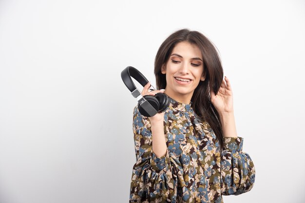 Jonge vrouw poseren met koptelefoon op witte achtergrond.