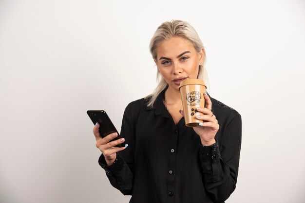 Jonge vrouw poseren met mobiele telefoon en kopje koffie. Hoge kwaliteit foto