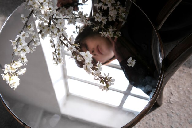 Jonge vrouw poseren met spiegel op stoel en bloem
