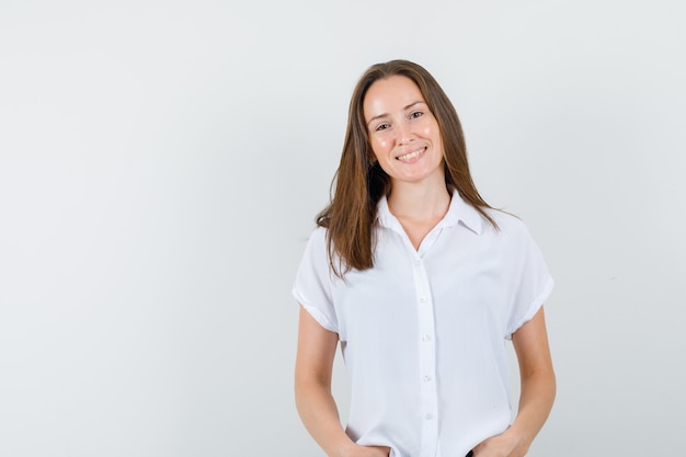 Jonge vrouw poseren tijdens het glimlachen in witte blouse en ziet er prachtig uit