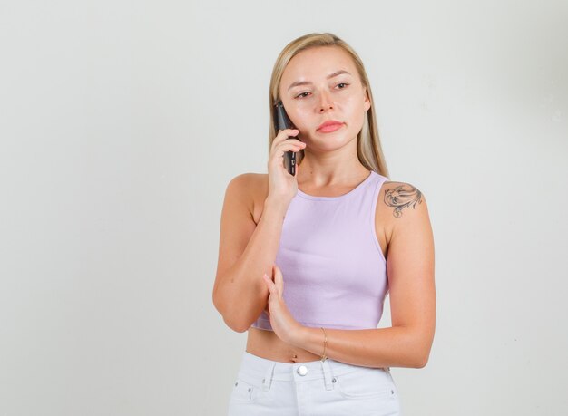 Jonge vrouw praten over smartphone in singlet