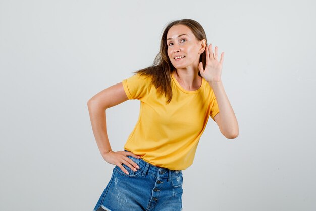 Jonge vrouw probeert iets vertrouwelijks te horen in een t-shirt, korte broek