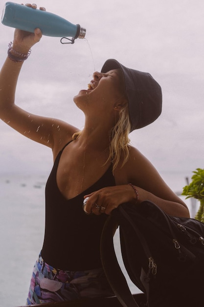 Jonge vrouw reiziger drinkt water uit een gekleurde fles.