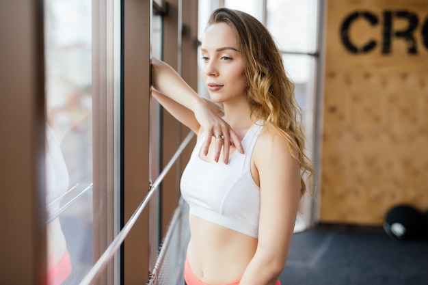 Jonge vrouw rusten na training bij sportschool. Fitness vrouw pauze na trainingssessie in gezondheidsclub.