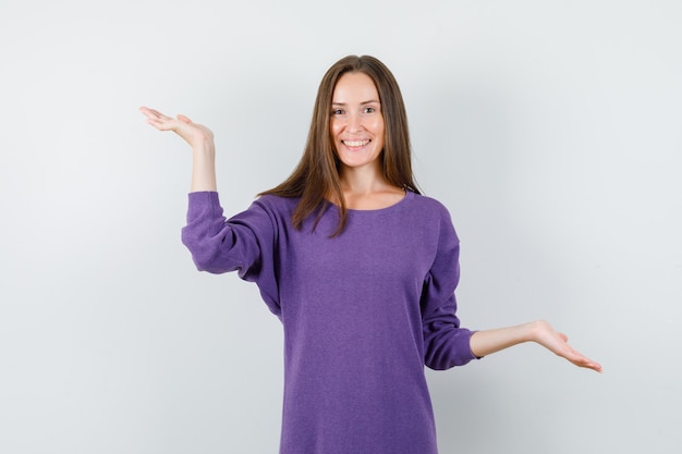 Jonge vrouw schalen gebaar maken in violet overhemd en op zoek gelukkig. vooraanzicht.