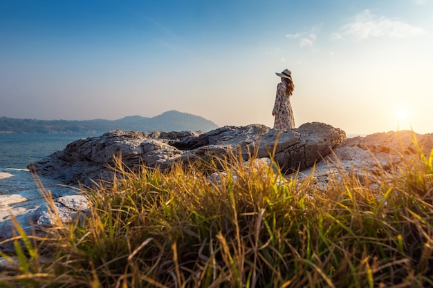 Jonge vrouw staande op de top van de rots bij zonsondergang in Si Chang Island.