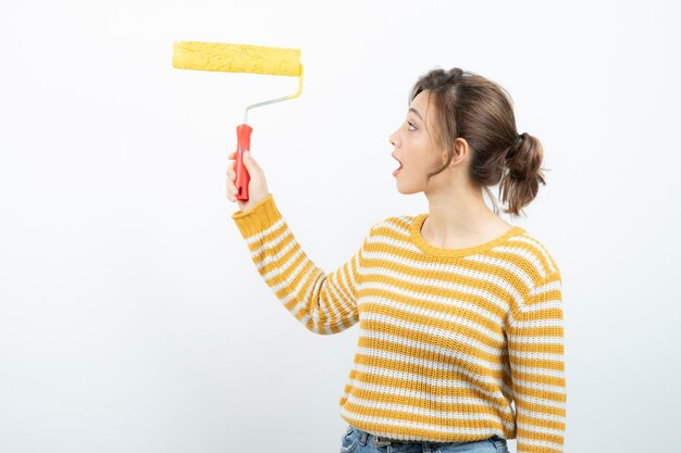 jonge vrouw staat en houdt een verfroller in haar hand.