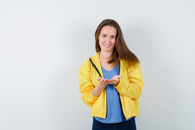 Jonge vrouw staat met holle handen in t-shirt en ziet er vrolijk uit. vooraanzicht.