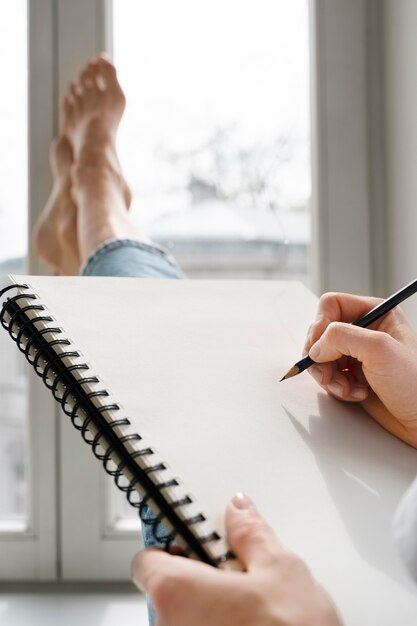 Jonge vrouw tekening thuis in de buurt van het raam