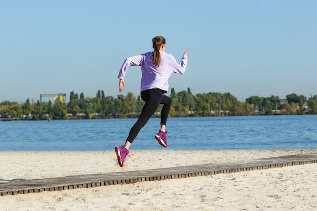 Gratis foto jonge vrouw traint buiten in de herfstzon. begrip sport