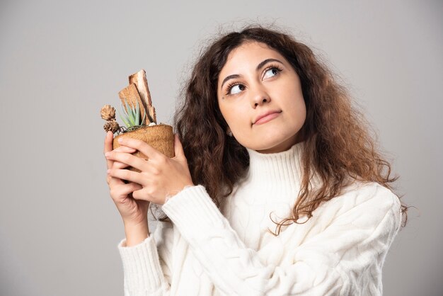 Jonge vrouw tuinman met een plant op een grijze muur. Hoge kwaliteit foto