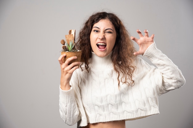 Jonge vrouw tuinman met een plant op een grijze muur. Hoge kwaliteit foto