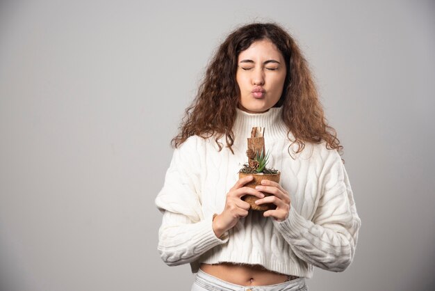 Jonge vrouw tuinman met een plant op een grijze muur. Hoge kwaliteit foto