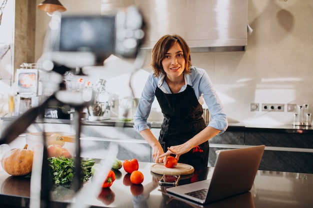 Jonge vrouw videoblogger koken in de keuken en filmen