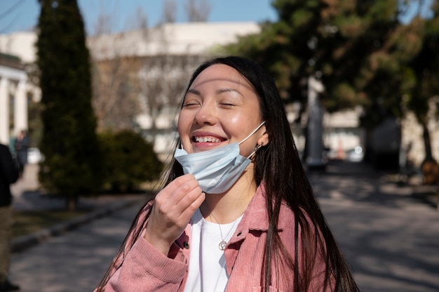 Jonge vrouw viert het opheffen van de beperkingen van gezichtsmaskers buiten in de stad