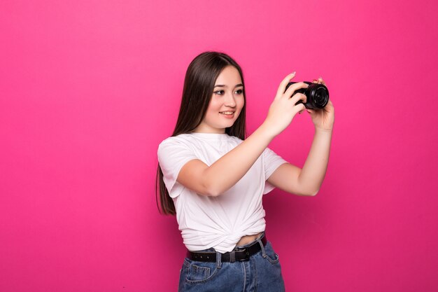 Jonge vrouw vrolijk met fotocamera op roze muur