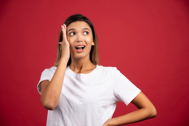 Jonge vrouw wat betreft haar gezicht op rode muur