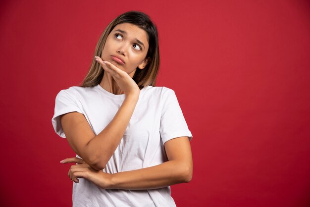 Jonge vrouw wat betreft haar gezicht op rode muur