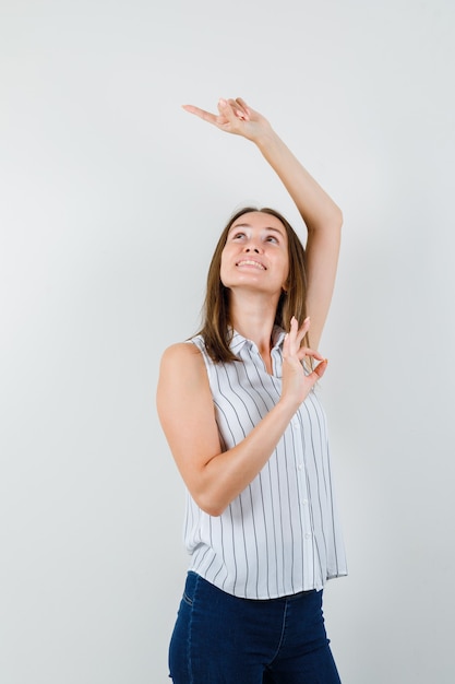 Gratis foto jonge vrouw wijst weg in t-shirt, spijkerbroek en kijkt gericht. vooraanzicht.