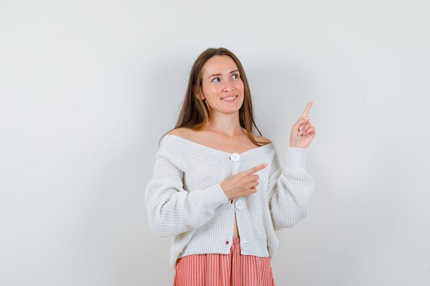 Jonge vrouw wijzend op de rechterbovenhoek op zoek hoopvol geïsoleerd