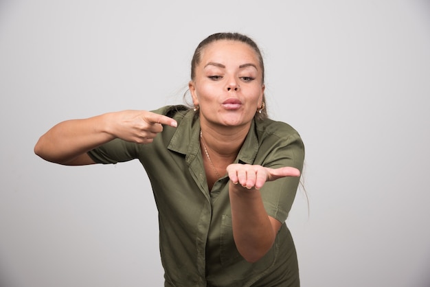 Jonge vrouw wijzend op haar hand op grijze muur.