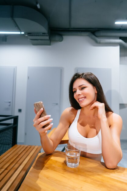 Jonge vrouw zitten en het gebruik van smartphone na de training