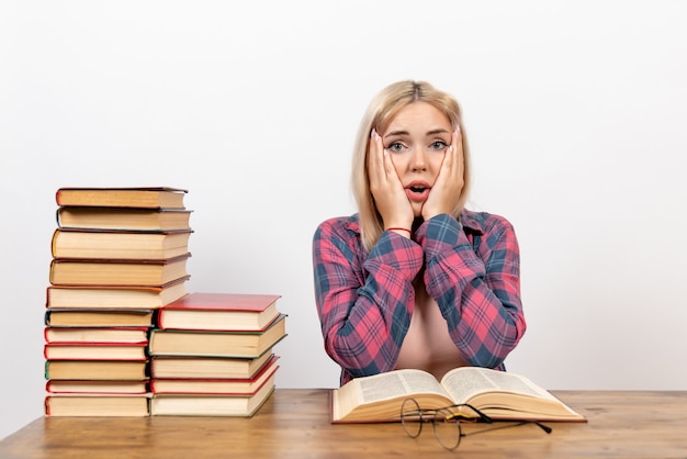 Gratis foto jonge vrouw zitten met boeken en lezen die zich voordeed op wit