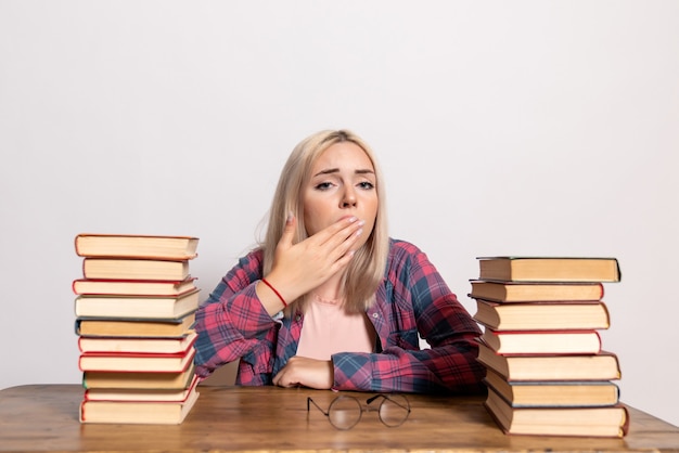 Gratis foto jonge vrouw zitten met boeken moe op wit